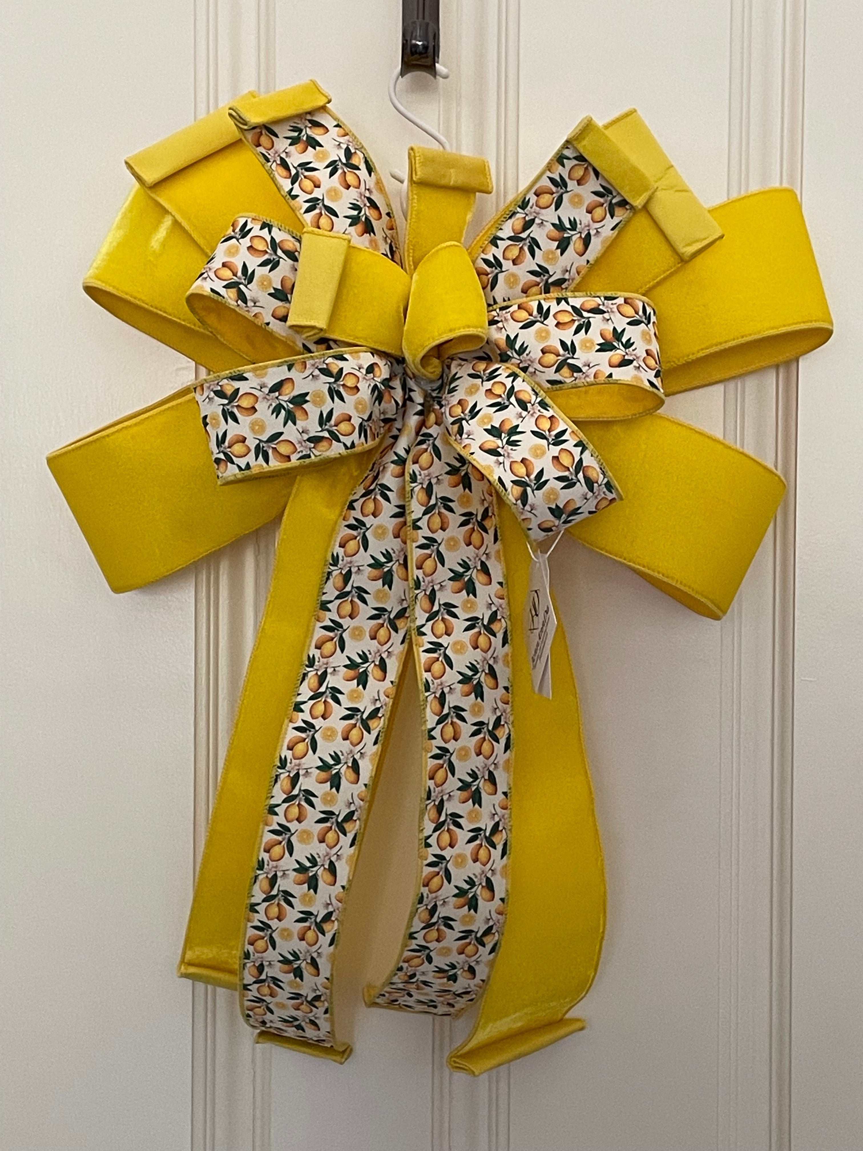 Large decorative bow for wreaths or door hangers comprised of a 4" Farrisilk lemon yellow velvet ribbon and a 2.5" Farrisilk white with lemons ribbon on a neutral background