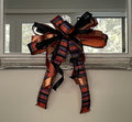 Halloween bow comprised of 2.5" black, orange, purple, and lime ribbon with an orange sating backing, 1.5" Metallic Copper Lame Ribbon, and 7/8" black satin hung from the bottom of a mirror.