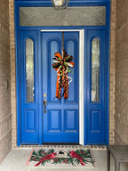 Wide angle view of a bow comprised of 4" Orange w/ black backing double-fused dupion ribbon 2.5"Orange w/ black flocked spiders and flocked black backing ribbon 1.5" d. stevens Black pleated metallic ribbon 1" White pleated metallic ribbon 1" Lime green ribbon with lime rhinestone center hanging from a blue door