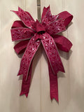 Large decorative bow for wreaths or door hangers comprised of a 4" Farrisilk pink embroidered and sequined ribbon and a 2.5" Farrisilk pleated metallic hot pink ribbon on a neutral background