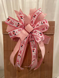 Large decorative bow for wreaths or door hangers comprised of a 2.5" 2" Rose Pink Dupion ribbon and a 2.5" Pink valentines gnomes ribbon on a neutral background