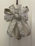 Large decorative bow for wreaths or door hangers comprised of sparkling 2.5" Farrisilk pleated metallic platinum ribbon and dazzling 2.5" d. stevens off white and heavily AB rhinestoned ribbon on a neutral background