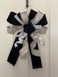 Large decorative bow for wreaths or door hangers comprised of a 4" Farrisilk black velvet ribbon, a 2.5" Farrisilk pleated metallic platinum ribbon, and a 1" Farrisilk white with silver sequin accent ribbon on a neutral background