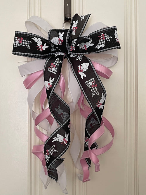 Large decorative bow for wreaths or door hangers comprised of a 4" Farrisilk white w/ black dots ribbon, a 2" black and white bunnies ribbon, a 1" light pink satin ribbon, and a 1" white flocked ribbon on a neutral background