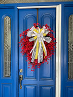 Wide view of a decorative wreath with dainty red flowers and a bow comprised of a 4" Farrisilk White w/ Black Polka Dots ribbon, a 2.5" Black and white chinoiserie ribbon, and a 1" white satin ribbon on a neutral colored door.